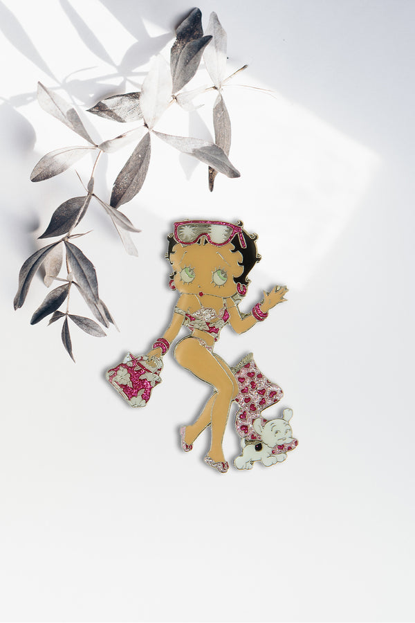 Betty Boop Fridge Magnet Beach Babe Betty is in a flowery beach wear in pink and white posing with her pet pudgy. This fridge magnet sticks easily to the fridge or any other magnetic surface where magnets can stick to. Exclusively Available at Reliance Gifts www.reliancegifts.co.uk